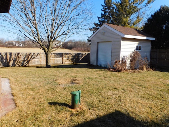 view of yard featuring a fenced backyard, a detached garage, and an outdoor structure