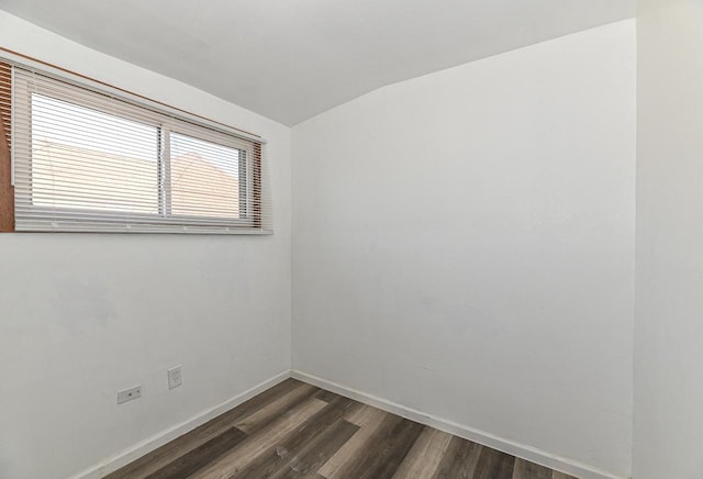 unfurnished room featuring dark wood finished floors, baseboards, and lofted ceiling