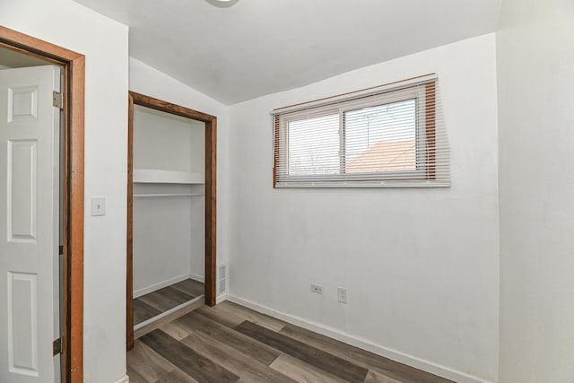 unfurnished bedroom with wood finished floors, visible vents, baseboards, vaulted ceiling, and a closet