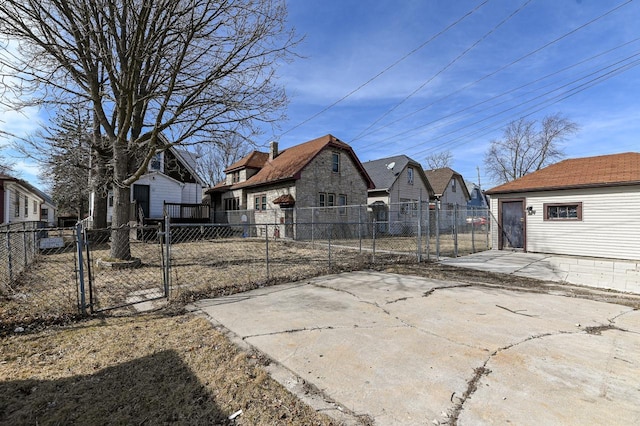 exterior space featuring concrete driveway, an outdoor structure, a detached garage, fence private yard, and a residential view