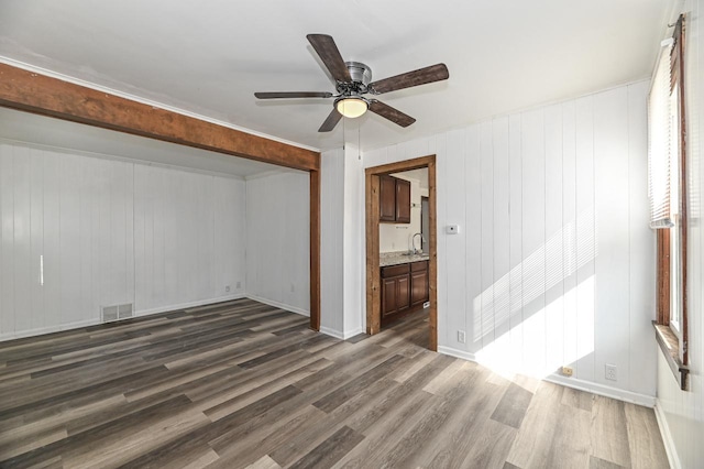 interior space with visible vents, a ceiling fan, a sink, wood finished floors, and baseboards