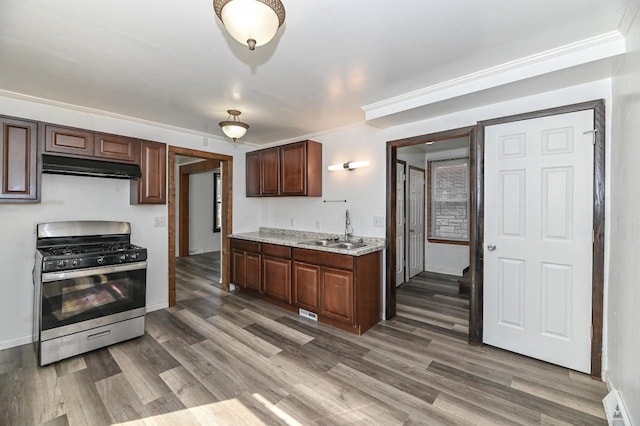 kitchen featuring under cabinet range hood, gas stove, wood finished floors, and a sink