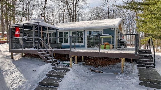 snow covered house featuring stairs and a wooden deck