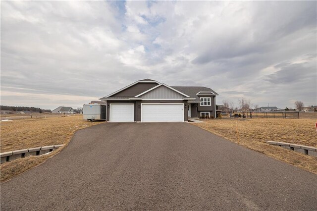 view of front facade featuring aphalt driveway, an attached garage, and fence