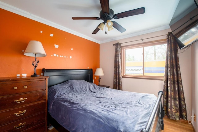 bedroom featuring light wood finished floors, crown molding, and a ceiling fan