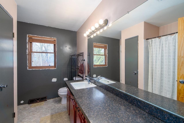 full bathroom featuring toilet, plenty of natural light, vanity, and visible vents