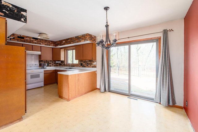 kitchen with visible vents, light floors, light countertops, a peninsula, and white electric range oven