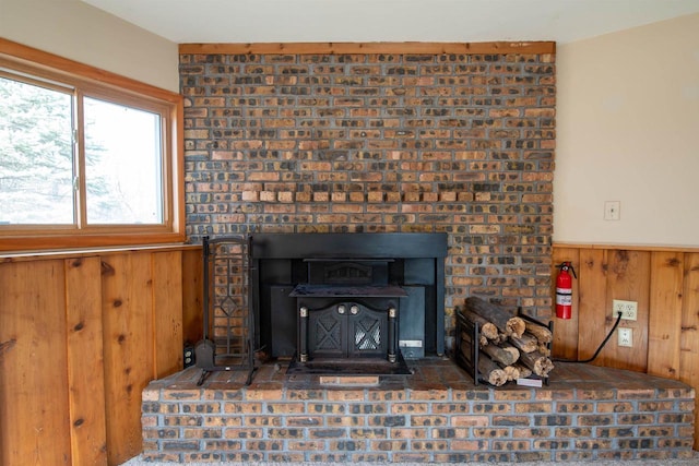 room details with a wainscoted wall, wood walls, a wood stove, and a fire extinguisher