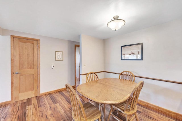 dining area featuring light wood-style flooring and baseboards