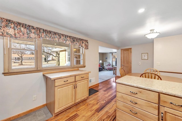 kitchen featuring light wood-style flooring, baseboards, visible vents, and light brown cabinetry