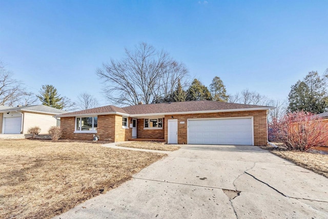 single story home with concrete driveway, an attached garage, and brick siding