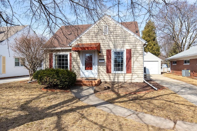 bungalow-style home featuring an outdoor structure, a garage, central AC, and roof with shingles