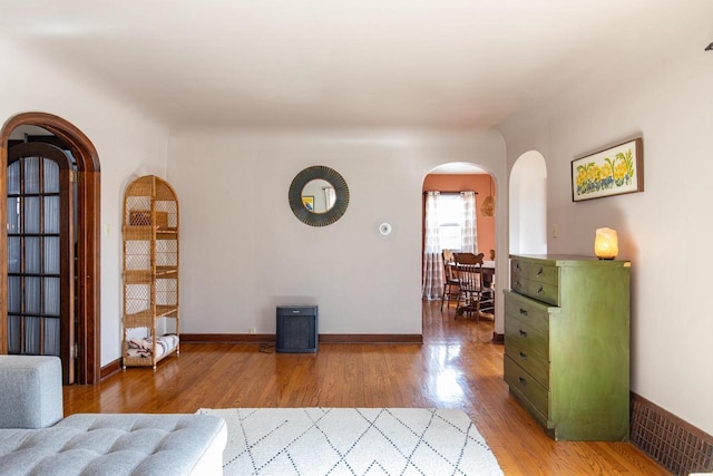 interior space featuring wood finished floors, arched walkways, and baseboards