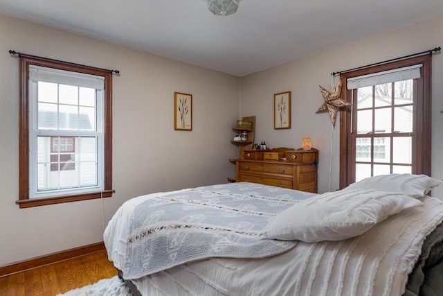 bedroom featuring baseboards, multiple windows, and wood finished floors