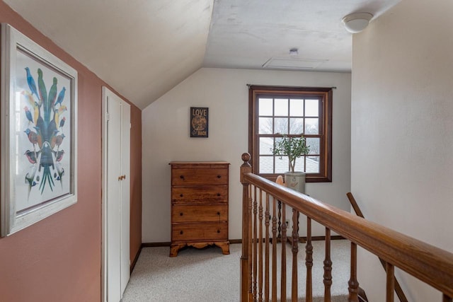 corridor with baseboards, attic access, vaulted ceiling, an upstairs landing, and light colored carpet