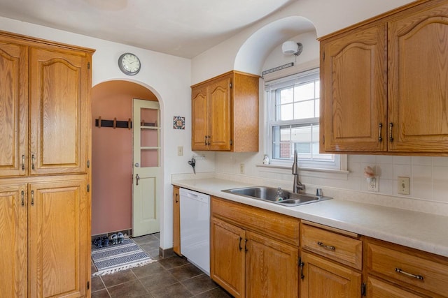 kitchen with tasteful backsplash, dishwasher, light countertops, brown cabinetry, and a sink