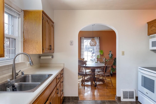 kitchen with visible vents, light countertops, electric stove, arched walkways, and a sink