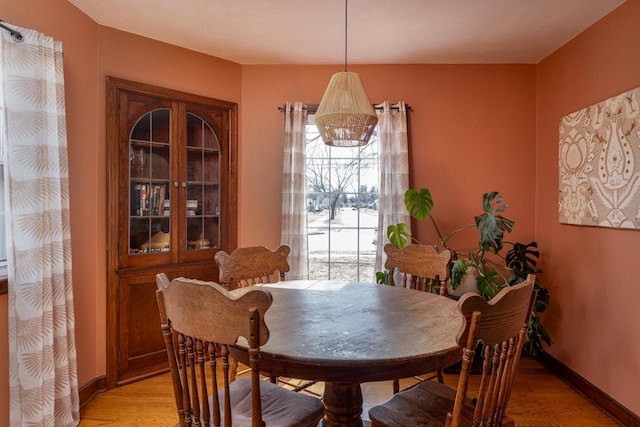 dining space featuring light wood-style floors and baseboards