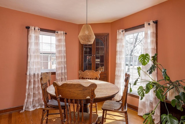 dining room with light wood-style flooring, plenty of natural light, and baseboards