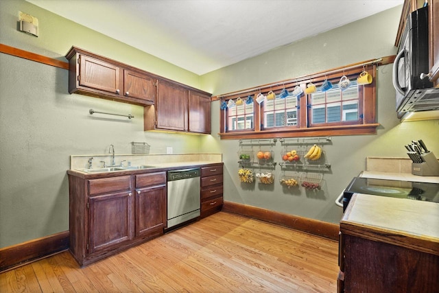 kitchen with light wood finished floors, a sink, appliances with stainless steel finishes, light countertops, and baseboards