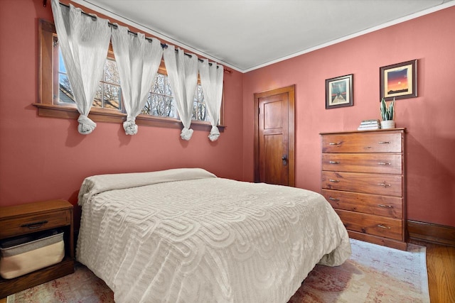 bedroom with wood finished floors and ornamental molding