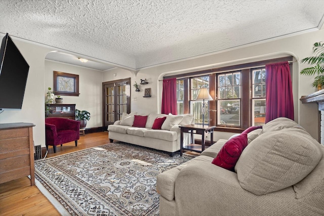 living area featuring a textured ceiling, wood finished floors, and ornamental molding