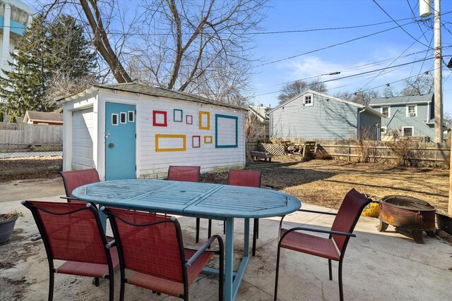 view of patio / terrace with an outbuilding, outdoor dining area, a garage, and fence