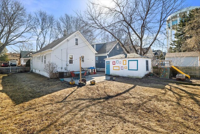 back of house with fence, a chimney, an outdoor structure, a playground, and a patio area