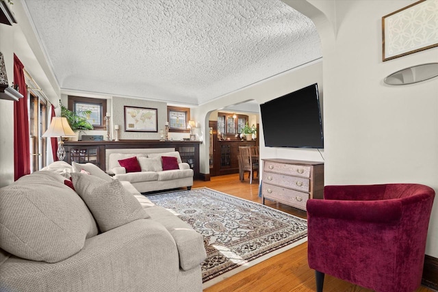 living area with wood finished floors, arched walkways, and a textured ceiling