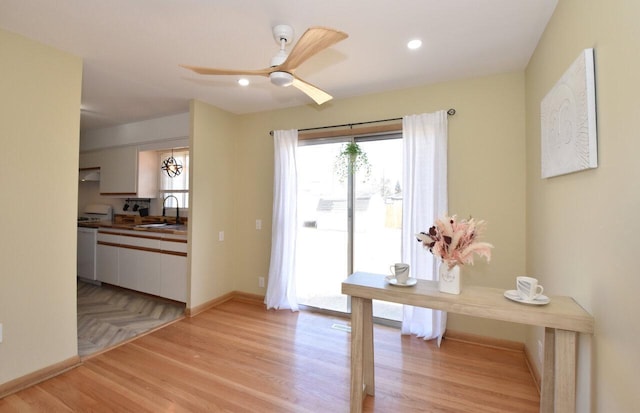 doorway with baseboards, ceiling fan, recessed lighting, light wood-style flooring, and a sink