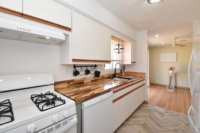 kitchen with white appliances, a sink, white cabinets, under cabinet range hood, and wood counters