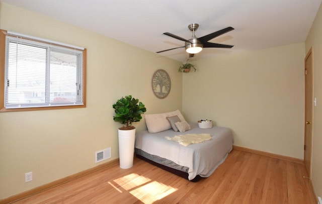 bedroom featuring light wood-style flooring, baseboards, visible vents, and ceiling fan