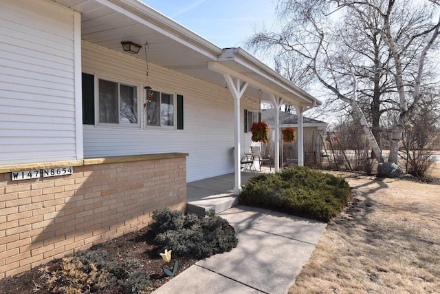 doorway to property with brick siding and covered porch