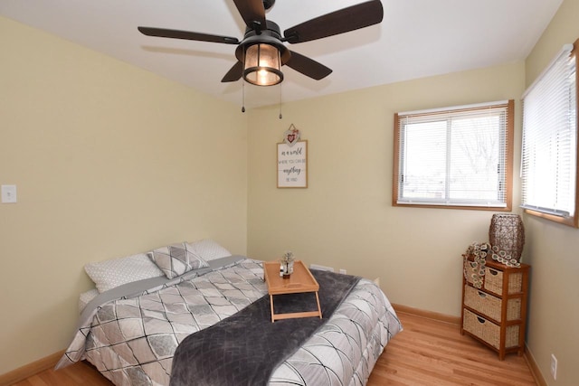 bedroom featuring ceiling fan, baseboards, and wood finished floors