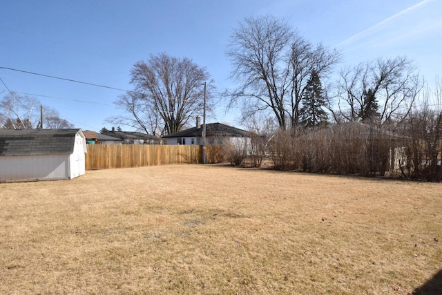 view of yard featuring an outdoor structure, fence, and a shed