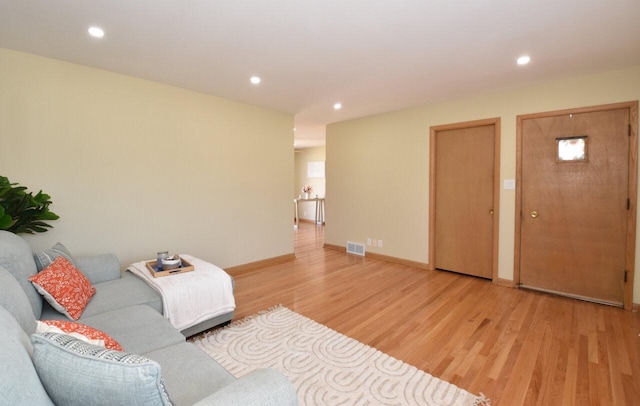 living room with recessed lighting, visible vents, baseboards, and light wood finished floors