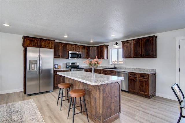 kitchen featuring dark brown cabinetry, appliances with stainless steel finishes, a textured ceiling, and a sink