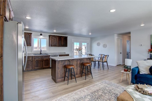 kitchen with a breakfast bar area, freestanding refrigerator, a sink, a wealth of natural light, and a center island