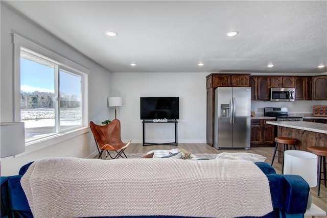 living area with recessed lighting, light wood-style floors, and baseboards