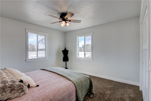 carpeted bedroom with ceiling fan, a textured ceiling, and baseboards