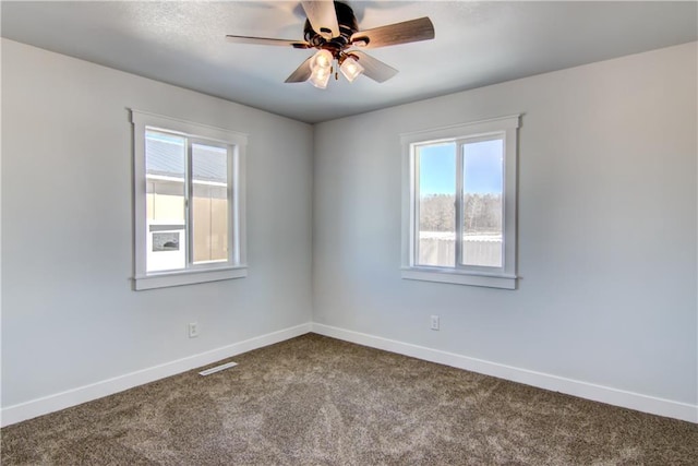 empty room with visible vents, ceiling fan, baseboards, and dark colored carpet