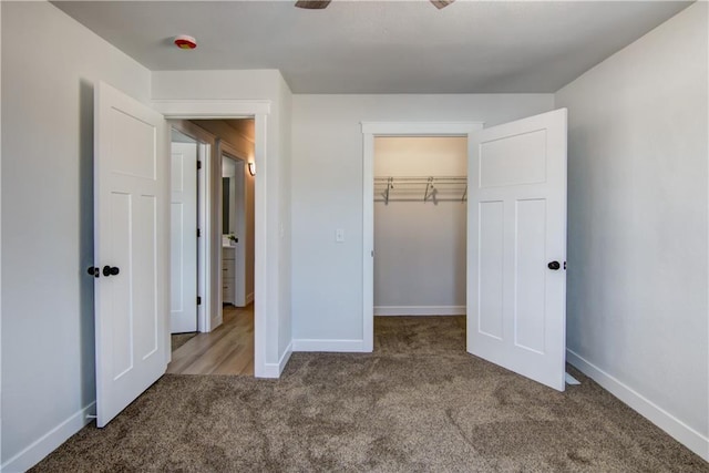 unfurnished bedroom with a closet, baseboards, carpet, and a spacious closet