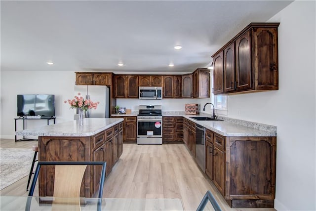 kitchen featuring light wood-style flooring, a center island, appliances with stainless steel finishes, and a sink