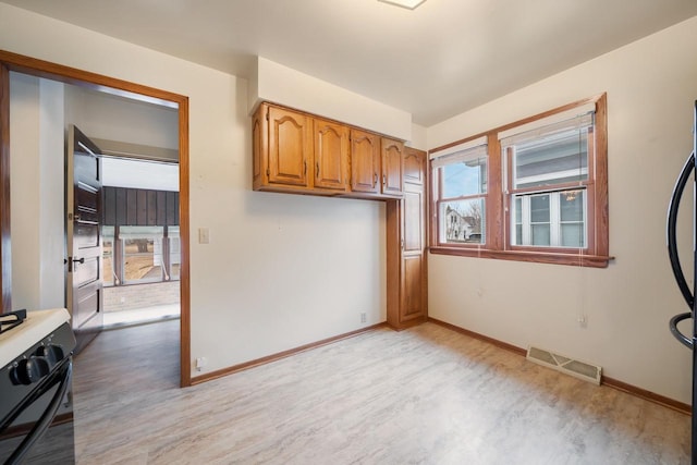 interior space featuring brown cabinetry, visible vents, gas stove, and baseboards