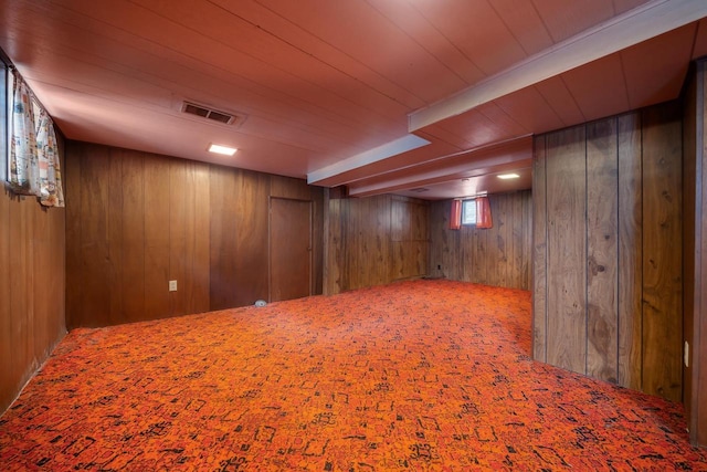 basement with visible vents, wood walls, wooden ceiling, and carpet flooring