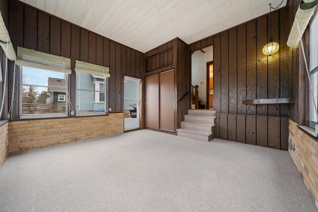 interior space featuring wooden walls, brick wall, and stairs