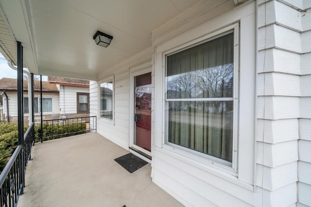 entrance to property featuring a porch and brick siding