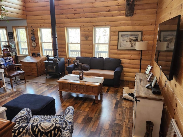 living room with log walls, a wood stove, and hardwood / wood-style flooring