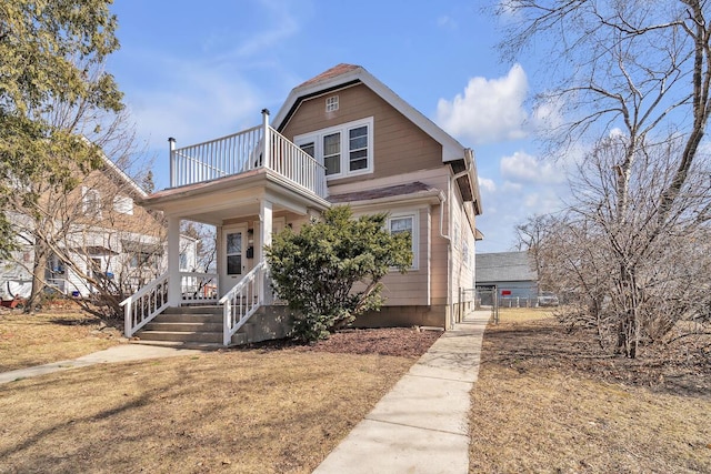 view of front of house with covered porch, a balcony, and a gate