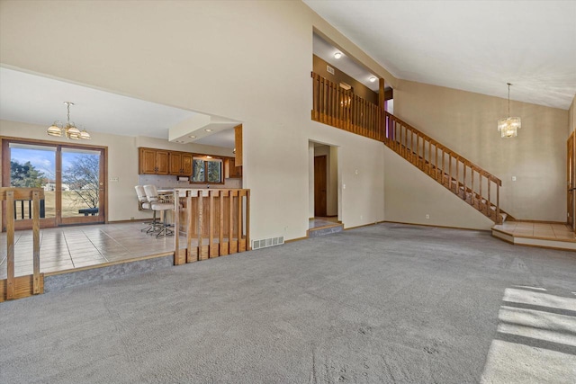 unfurnished living room with visible vents, light colored carpet, an inviting chandelier, and stairs